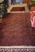 A large Middle Eastern wool floor rugs decorated with central geometric panel on a red background,