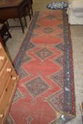 Middle Eastern runner carpet decorated with large red central panel, very worn particularly to ends,