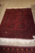 Middle Eastern wool floor rug decorated with six central lozenges on a red and black background, 185
