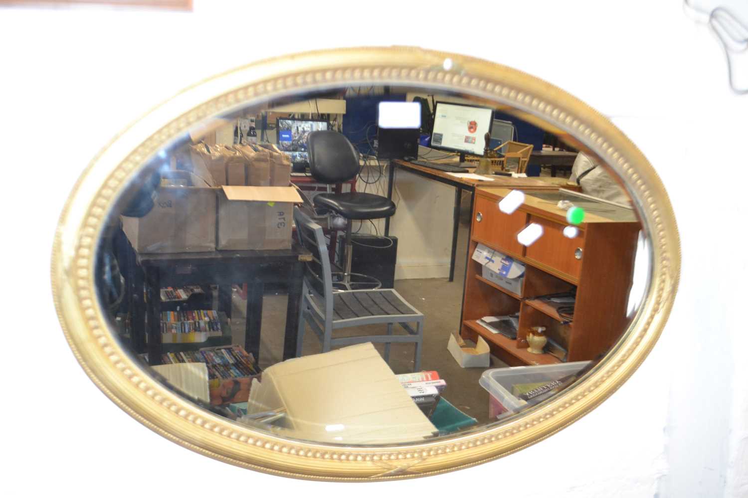 An oval bevelled wall mirror in gilt finish frame