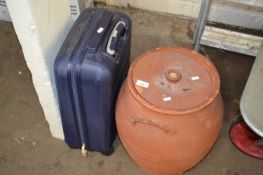 A terracotta egg crock and a small suitcase