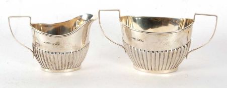 An Edwardian silver cream jug and twin handled sugar bowl oval shaped with part fluted design,