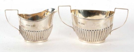 An Edwardian silver cream jug and twin handled sugar bowl oval shaped with part fluted design,