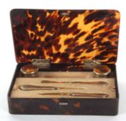 A George V silver manicure set in a tortoiseshell fitted box with silver hallmark hinges to the lid,