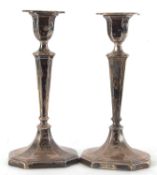 A pair of Edwardian candlesticks having detachable nozels with reed decorated tapering stems and