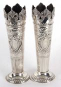 A pair of early 20th Century solid silver vases of tapering cylindrical form having shell and scroll