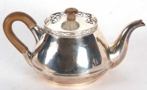 A George V silver teapot of squat circular form having a pierced rim, fruit wood turned finial and