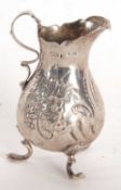 A late Victorian silver cream jug having a round bellied body with chased and embossed floral