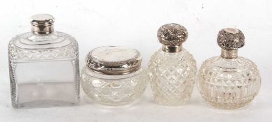 A group of four glass dressing table jars/bottles, each with hallmarked silver lids