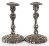 A pair of late Victorian silver candlesticks, elaborately embossed all over with scrolls, beads