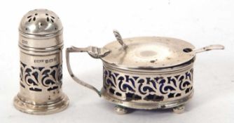 A hallmarked silver mustard with blue glass liner of oval pierced form with shell thumb piece to a