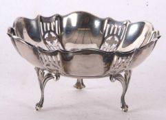 A George V silver circular bonbon dish, having fluted and pierced sides, supported on three