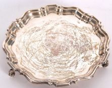 An Elizabeth II silver card salver with a deep pie crust edge, plain ground, supported on three