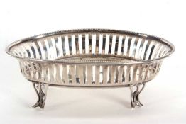 An Edwardian silver oval dish having pierced geometric designed sides and beaded rim, supported on