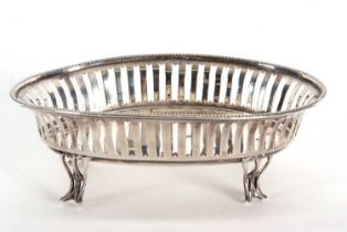 An Edwardian silver oval dish having pierced geometric designed sides and beaded rim, supported on