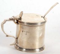 An Edwardian silver drum mustard of plain form, the hinged lid with a shell thumb piece, having