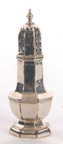 A George V silver caster of plain octagonal form, having a pull off lid with pierced geometric