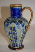 A Doulton Lambeth jug with mask to the spout and incised floral decoration, artists monogram to