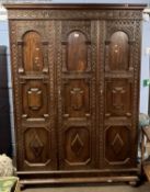 A large early 20th Century Jacobian Revival oak triple door wardrobe, 202cm high, 56cm deep and