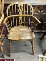 A small Victorian elm seated Windsor type low armchair with turned legs and H formed stretcher