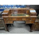 An Edwardian Carlton House style small writing table with a curved back, various drawers and storage