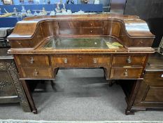 An Edwardian Carlton House style small writing table with a curved back, various drawers and storage