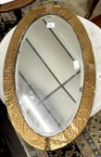A 20th Century oval bevelled wall mirror in an Arts & Crafts type planished copper mounted frame,