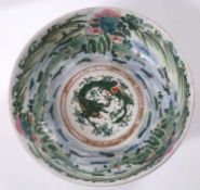A Japanese porcelain bowl with famille vert decoration of landscape and dragons, 22cm diameter