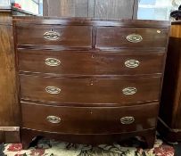 A late Georgian mahogany bow front chest of two short over three long drawers, fitted with oval