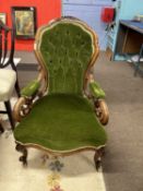 A Victorian green button upholstered armchair with scrolled arms, short cabriole legs and casters