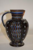 A Doulton Lambeth mask jug with incised floral designs and mask at the lip, dated 1879, 18cm high