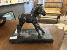 A bronzed finish iron model of a foal on an ebonised wooden base, 24cm long max