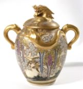 A Satsuma jar and cover with elephant mask handles and a floral design with birds in branches, the