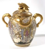 A Satsuma jar and cover with elephant mask handles and a floral design with birds in branches, the