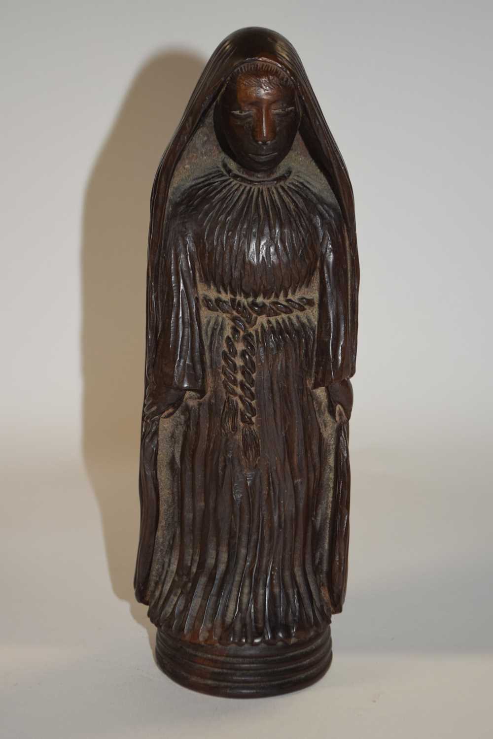 A carved wooden religious figure on circular base, 24cm high