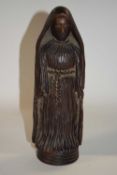 A carved wooden religious figure on circular base, 24cm high
