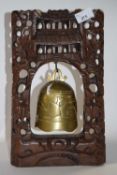A Chinese brass temple bell in carved wooden frame, 33cm high