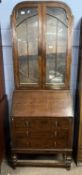 An early 20th Century oak bureau bookcase cabinet with glazed top section over a base with full