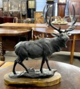 A black painted iron model of a stag set on wooden base, 47cm high