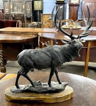 A black painted iron model of a stag set on wooden base, 47cm high