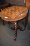 A Victorian pedestal games table with a veneered chess board top raised on a barley twist column and