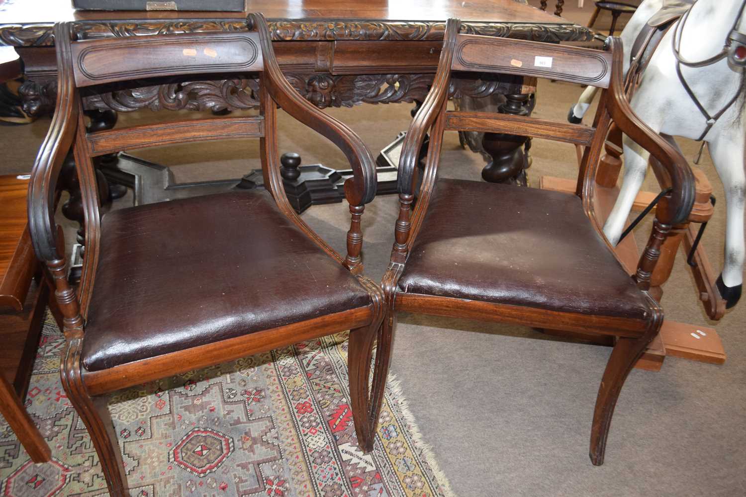 A pair of Georgian mahogany sabre leg carver chairs of typical form with drop in seats