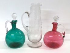 Two decanters, one green glass the other cranberry together with a further clear glass jug to