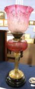 A 19th Century oil lamp, the brass Corinthian column with ruby glass reservoir and ruby/pink glass
