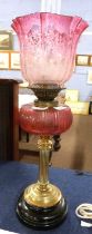 A 19th Century oil lamp, the brass Corinthian column with ruby glass reservoir and ruby/pink glass