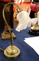 A brass desk lamp with frosted glass shade