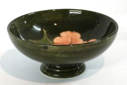 A small Moorcroft bowl decorated with hibiscus on a green ground with paper label to base, 14cm