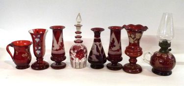 A collection of 19th Century cranberry glass wares including a small lamp with fruiting vine design,