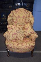 A Georgian style walnut framed wing back armchair with feather filled cushions