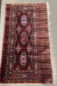 A Belouch wool wall hanging decorated with geometric patterns in red, blue and cream, 137cm wide (